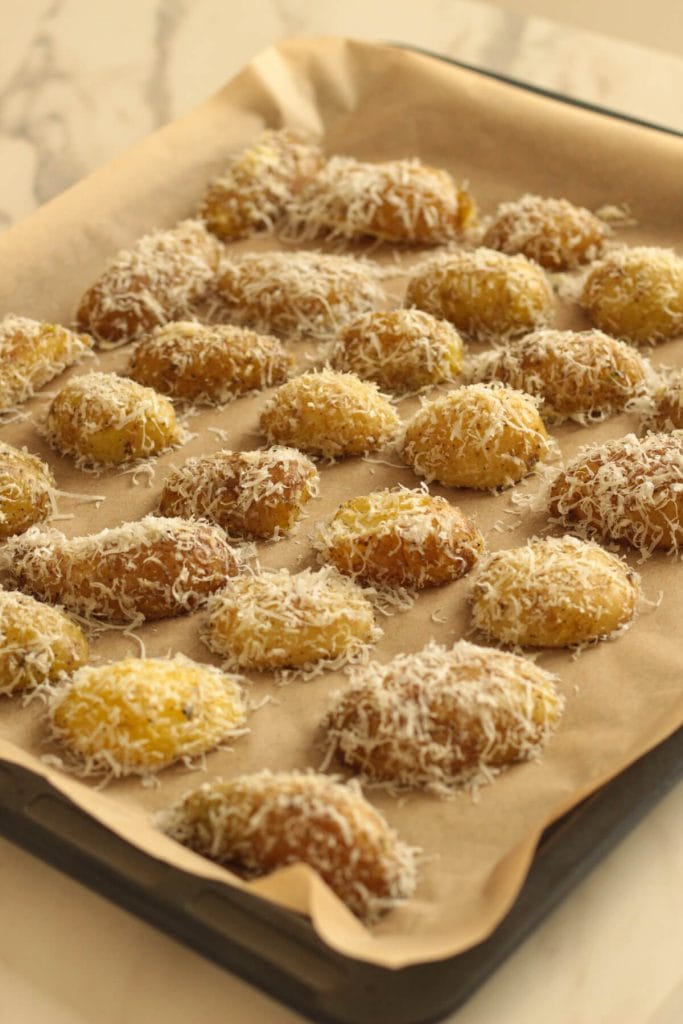 potatoes covered in parmesan on a tray