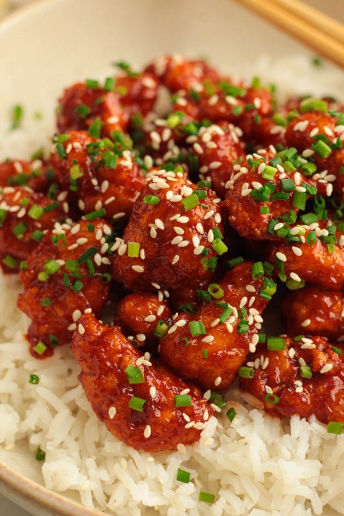 close up of Korean chicken bites in a bowl with sesame seeds and chives