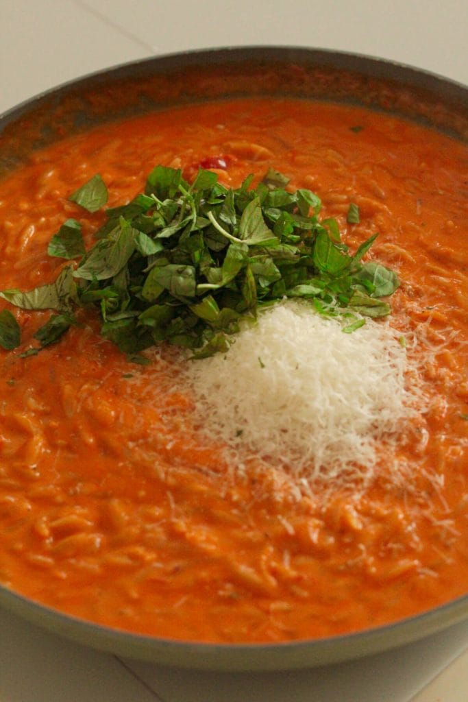 orzo with creamy sauce, parmesan and basil in a pan
