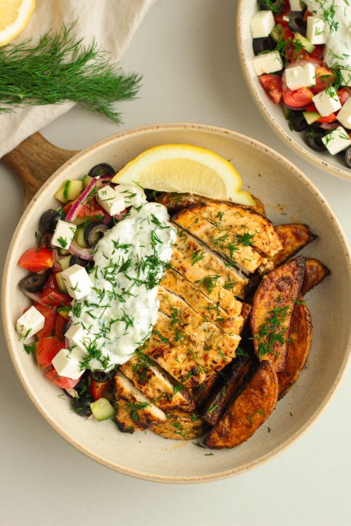 Greek-style lemon herb chicken breast with potatoes, tzatziki and Greek salad on the side