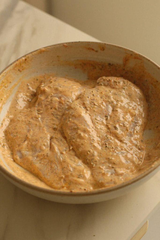 chicken breast marinating in a bowl