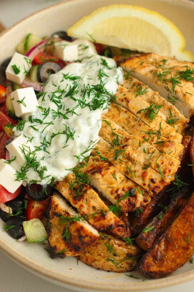 Greek-style lemon herb chicken breast with potatoes, tzatziki and Greek salad on the side