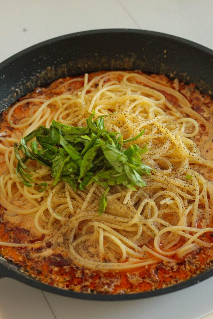 sun-dried tomato sauce with cooked spaghetti and fresh basil