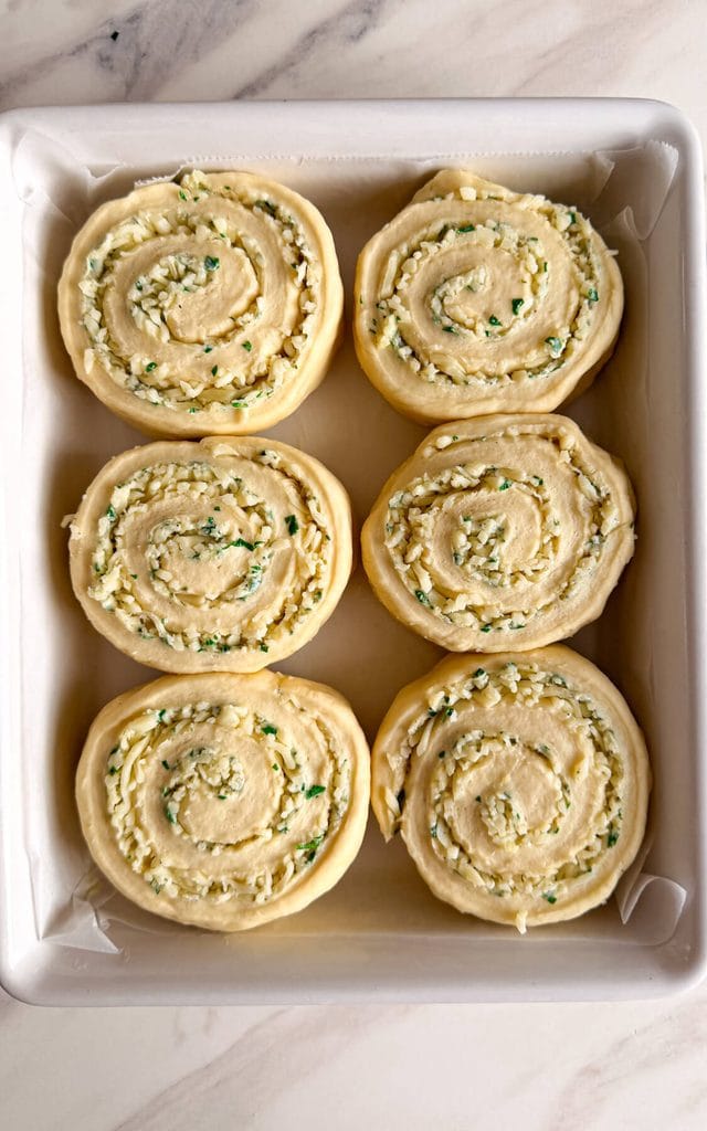 unbaked cheesy garlic rolls in a baking pan